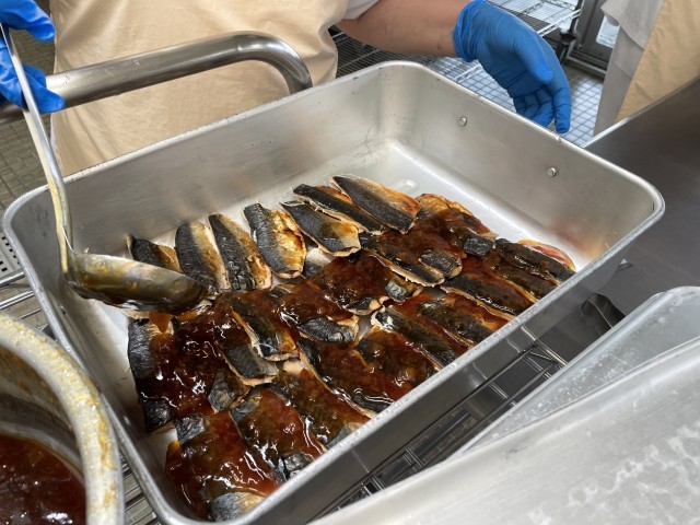 焼いたサバにたれをかける様子